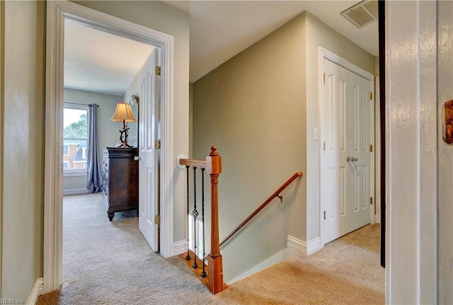 hall featuring an upstairs landing, visible vents, baseboards, and carpet