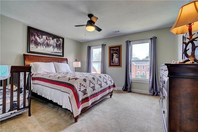 bedroom featuring visible vents, light colored carpet, a ceiling fan, and baseboards