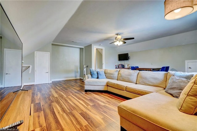 living area featuring ceiling fan, lofted ceiling, baseboards, and wood finished floors