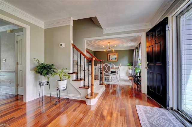 foyer entrance featuring stairs, crown molding, wood finished floors, and baseboards