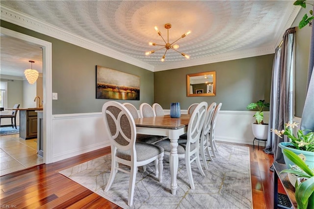 dining space featuring wood finished floors, a chandelier, and wainscoting