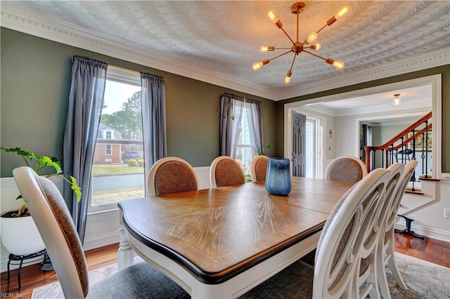 dining space featuring light wood-type flooring, a notable chandelier, ornamental molding, and stairway