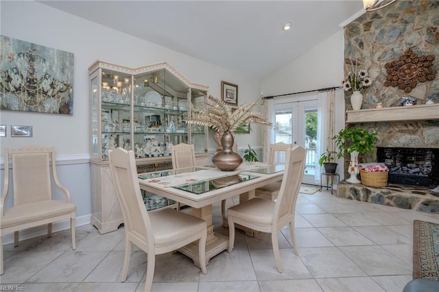 tiled dining room with a fireplace with raised hearth, french doors, and high vaulted ceiling