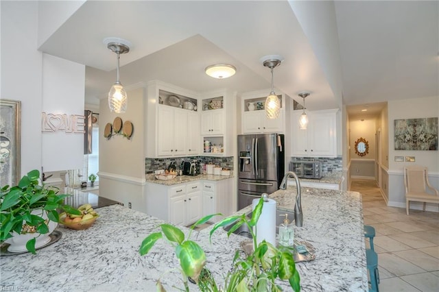 kitchen with light stone countertops, white cabinets, and stainless steel refrigerator with ice dispenser