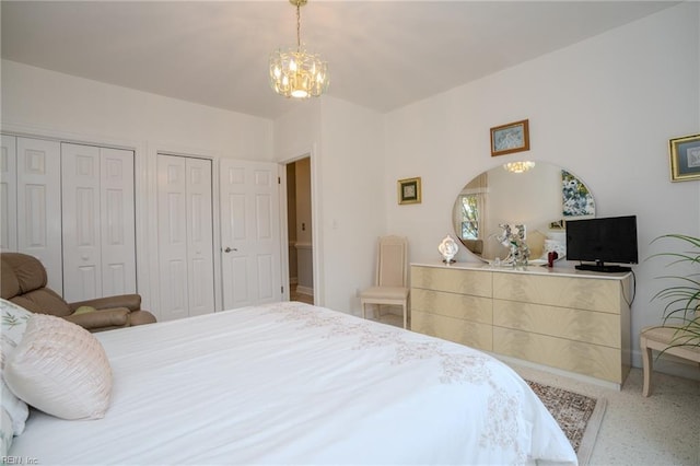 bedroom featuring speckled floor, two closets, and a chandelier