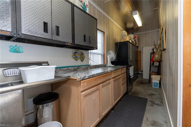 kitchen featuring dark countertops, wood walls, and concrete flooring