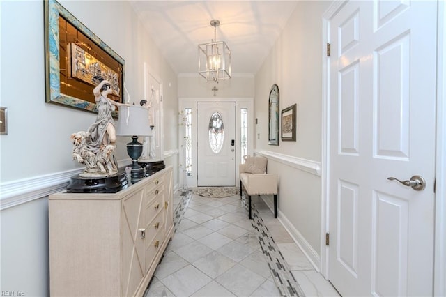 foyer with baseboards, an inviting chandelier, and ornamental molding