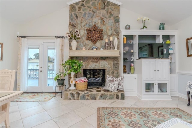 living area featuring light tile patterned floors, a stone fireplace, french doors, and high vaulted ceiling