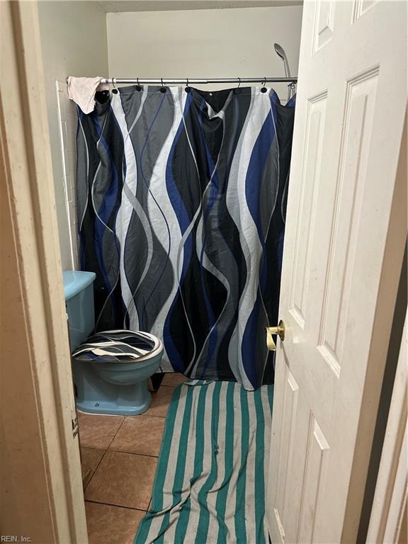 bathroom featuring curtained shower, toilet, and tile patterned flooring