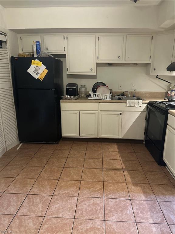 kitchen featuring light tile patterned floors, black appliances, light countertops, and a sink