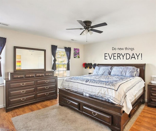 bedroom with dark wood-type flooring, a ceiling fan, and visible vents