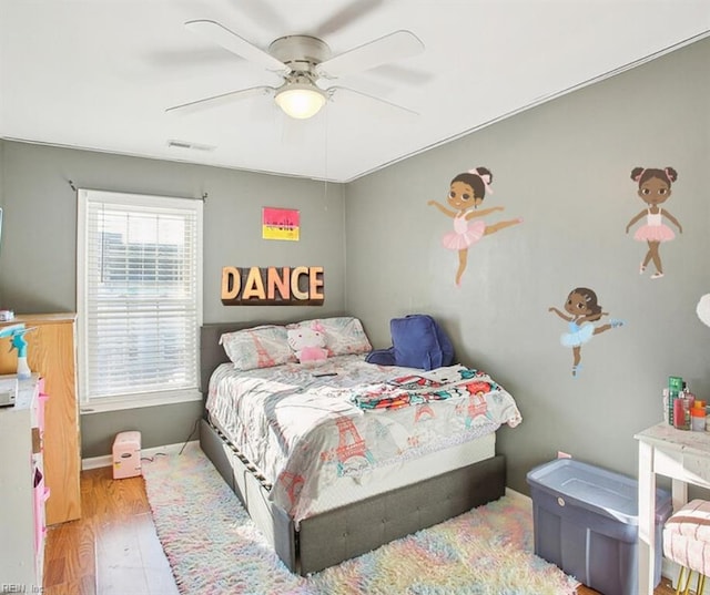 bedroom featuring visible vents, baseboards, a ceiling fan, and wood finished floors