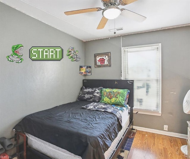 bedroom featuring visible vents, baseboards, ceiling fan, vaulted ceiling, and wood finished floors