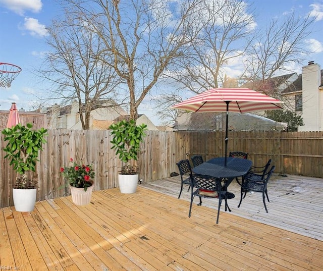 wooden terrace with outdoor dining area and a fenced backyard