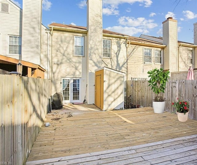 back of house with a wooden deck, fence private yard, a chimney, and a storage shed