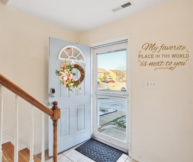 foyer entrance featuring light tile patterned floors, stairway, and visible vents