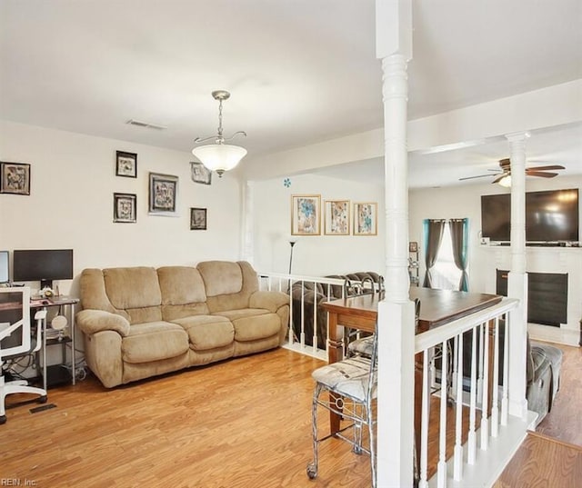 living room featuring ceiling fan, visible vents, ornate columns, and light wood-type flooring