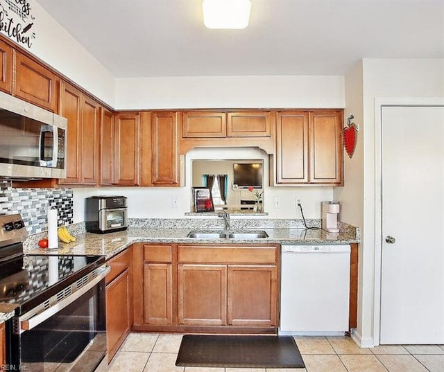 kitchen featuring a sink, light tile patterned floors, brown cabinets, and stainless steel appliances