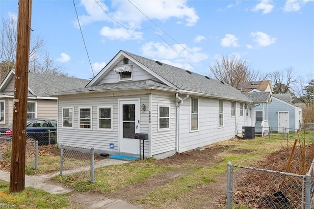 exterior space with central AC unit, a shingled roof, and fence