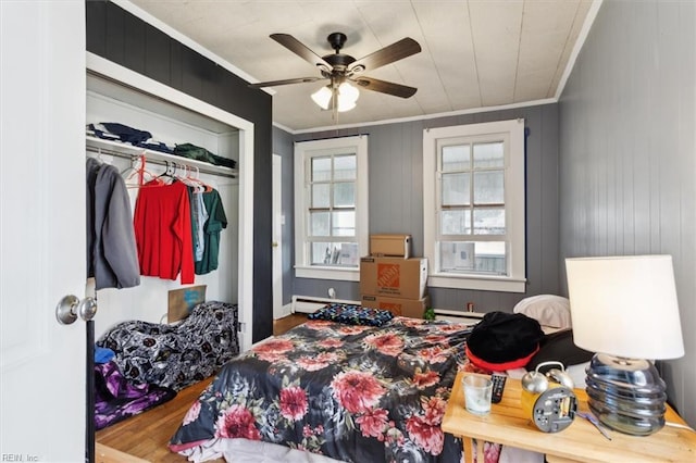 bedroom with a closet, a ceiling fan, wood finished floors, and crown molding