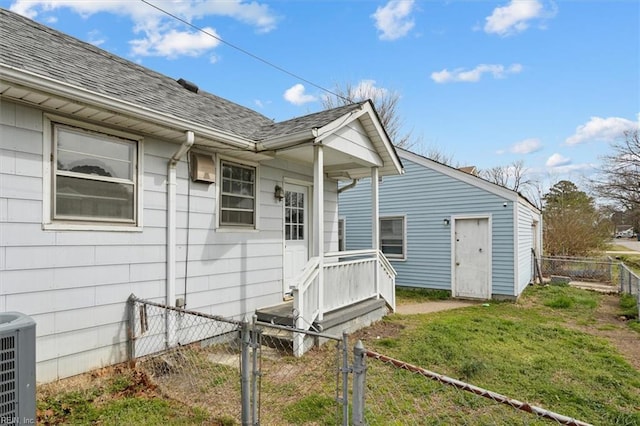 exterior space featuring a gate, central air condition unit, roof with shingles, and fence