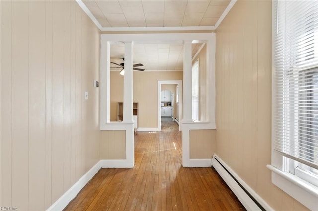 hall featuring a baseboard radiator, baseboards, crown molding, and hardwood / wood-style flooring