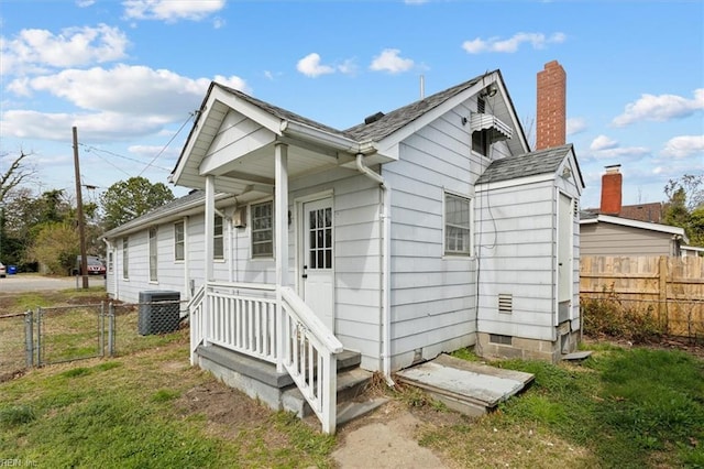 view of home's exterior featuring central AC unit, a gate, fence, and a lawn