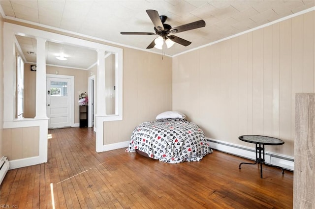 bedroom with baseboards, a baseboard radiator, ornamental molding, wood-type flooring, and baseboard heating