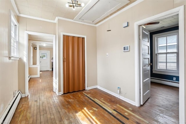 hall featuring a baseboard heating unit, hardwood / wood-style floors, crown molding, baseboard heating, and attic access