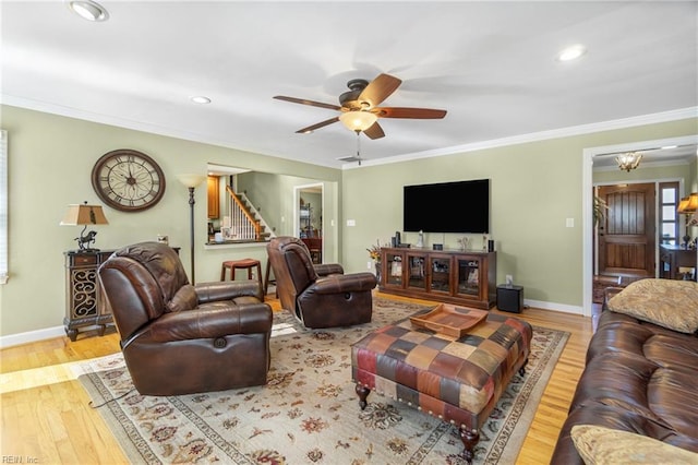 living area with wood finished floors, baseboards, and ornamental molding