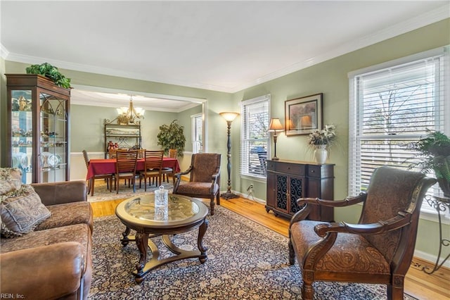 living room with baseboards, a notable chandelier, wood finished floors, and crown molding