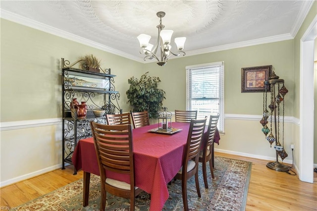 dining space with baseboards, an inviting chandelier, and wood finished floors