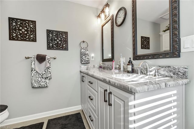 full bathroom with a sink, baseboards, toilet, and double vanity