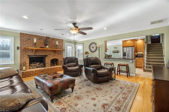 living room with light wood-style flooring, plenty of natural light, a fireplace, and visible vents