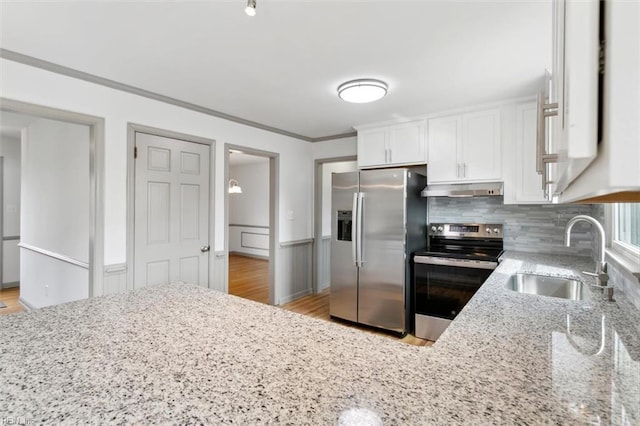 kitchen featuring a sink, under cabinet range hood, white cabinetry, appliances with stainless steel finishes, and crown molding