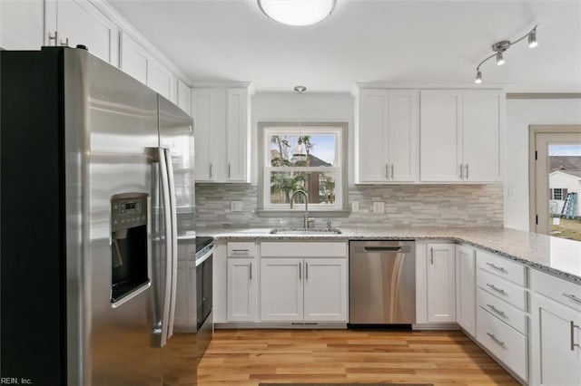 kitchen featuring white cabinetry, light wood-style floors, appliances with stainless steel finishes, and a sink