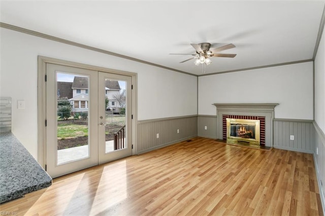 unfurnished living room featuring a fireplace, light wood finished floors, and wainscoting