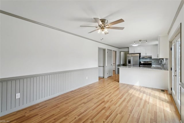 kitchen featuring light wood finished floors, white cabinets, stainless steel appliances, and ornamental molding