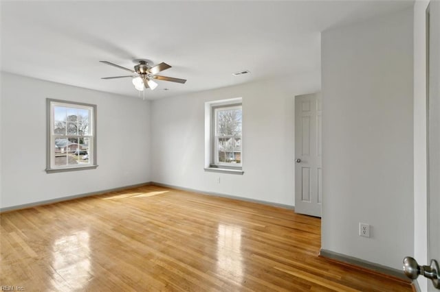 unfurnished room with visible vents, light wood-style flooring, a ceiling fan, and baseboards