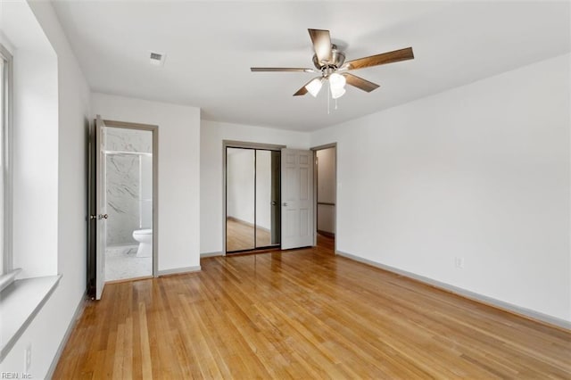 unfurnished bedroom featuring visible vents, baseboards, light wood-style flooring, a closet, and ensuite bath