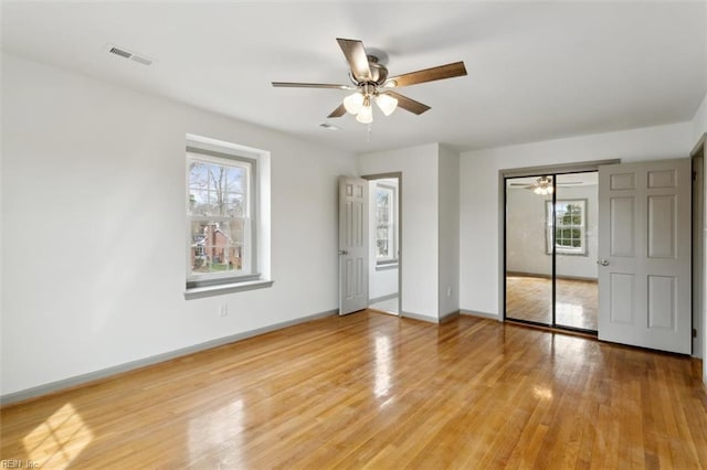 unfurnished bedroom featuring visible vents, baseboards, light wood-style flooring, ceiling fan, and a closet