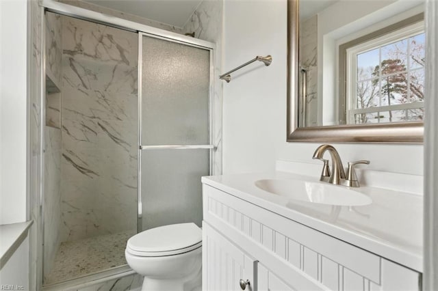 full bath with a marble finish shower, toilet, and vanity