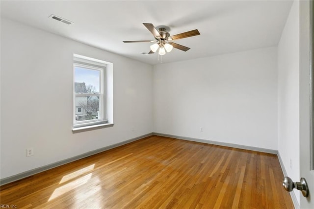 empty room with visible vents, a ceiling fan, light wood-type flooring, and baseboards