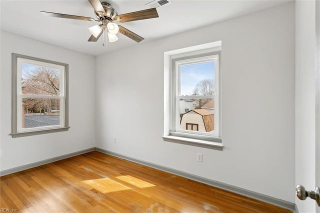 empty room featuring light wood-type flooring, baseboards, visible vents, and ceiling fan