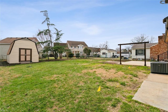 view of yard with fence, a residential view, cooling unit, a storage shed, and an outbuilding