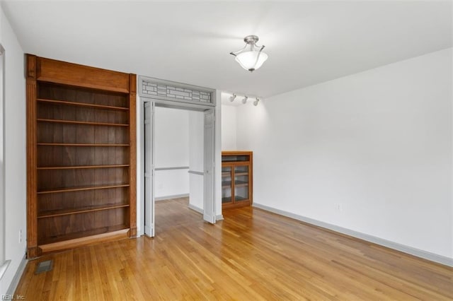 unfurnished bedroom featuring light wood-style flooring, visible vents, a closet, and baseboards