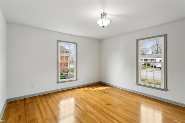 empty room with a healthy amount of sunlight, light wood-style floors, and baseboards