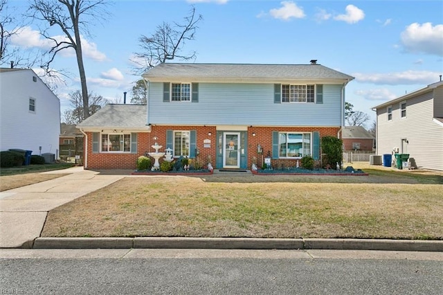 view of front of house with brick siding, central AC unit, concrete driveway, and a front lawn