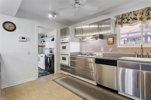 kitchen with under cabinet range hood, white appliances, backsplash, and washing machine and clothes dryer