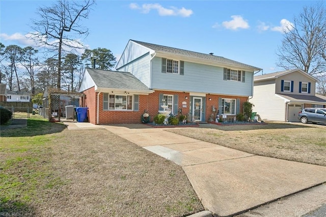 view of front of home featuring brick siding, driveway, a front yard, and fence